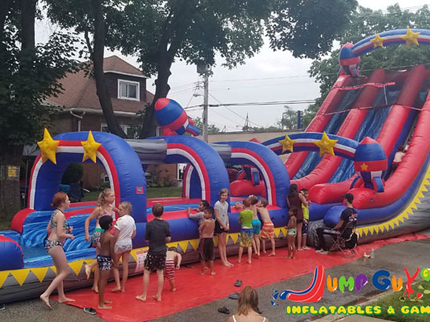 Kids sliding down a giant inflatable water slide at a Chicago backyard party